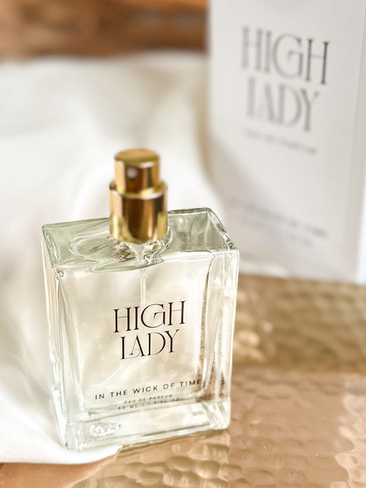 Perfume bottle labeled 'High Lady' on a reflective surface with a blurred background