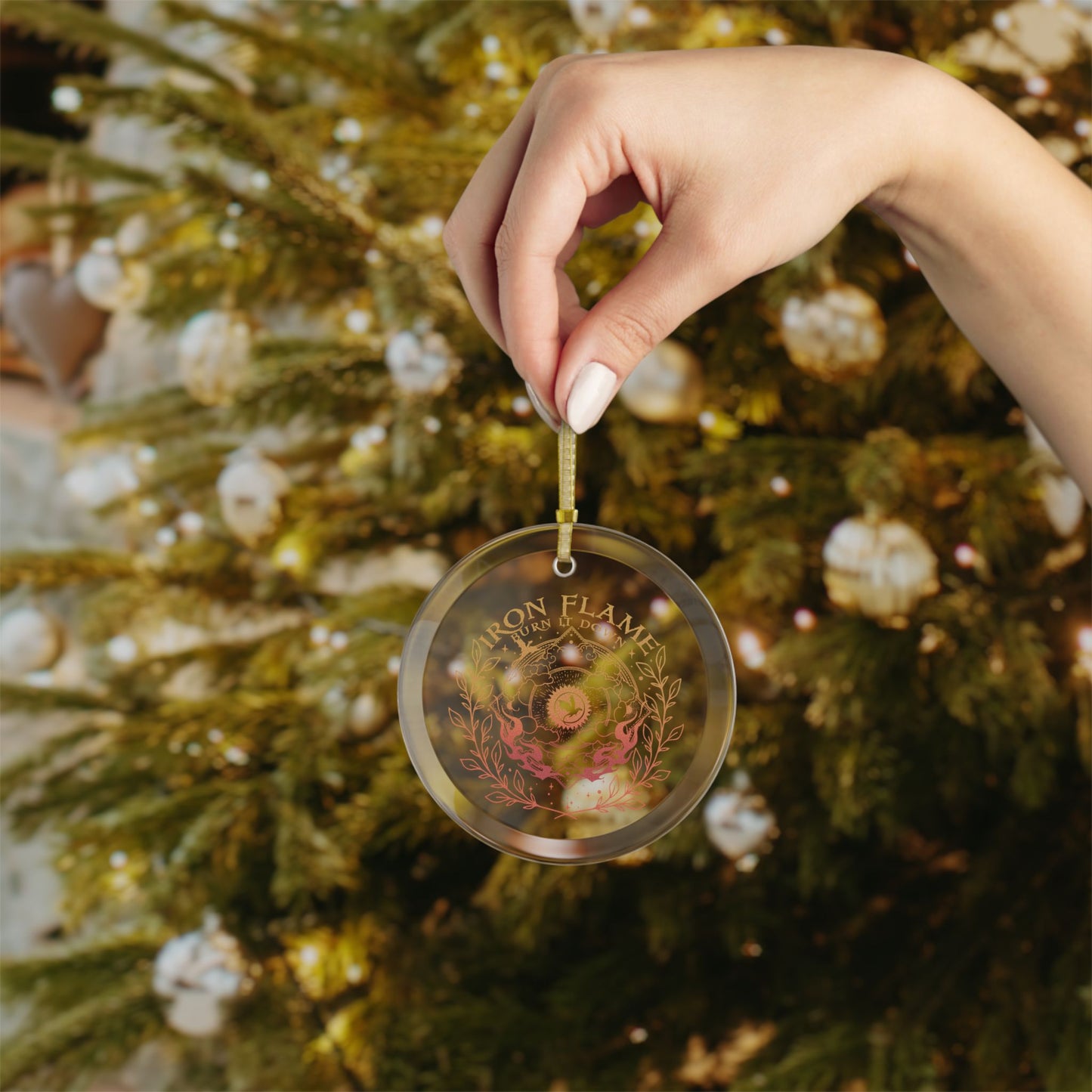 Hand holding a personalized Christmas ornament in front of a decorated tree