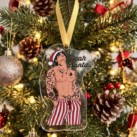 A clear acrylic Christmas ornament shaped like Santa's silhouette, featuring an illustration of a tattooed man in a Santa hat and red-and-white striped pants, with the text 'Dear Santa.