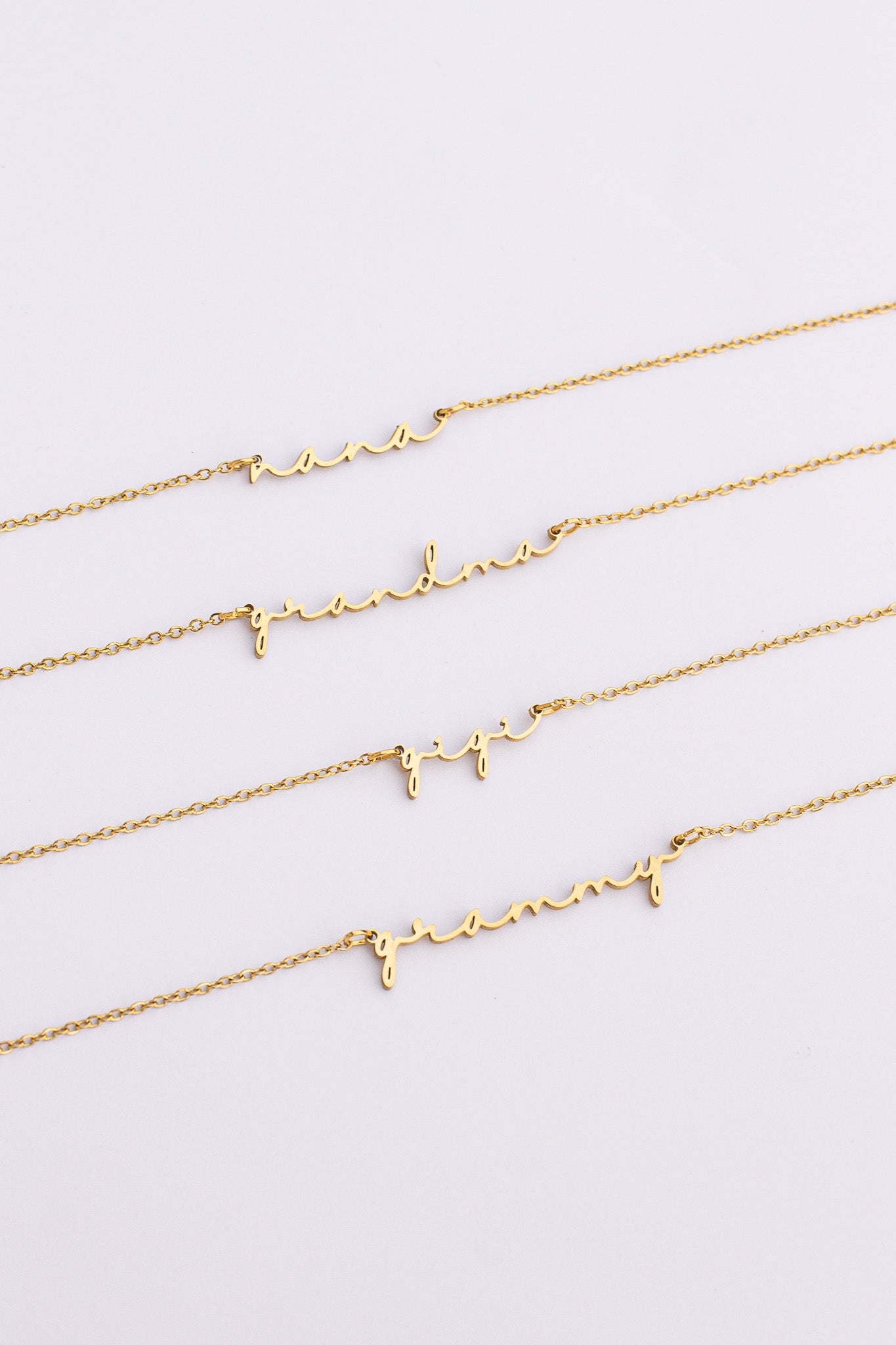 Three gold necklaces with letter pendants on a light gray background