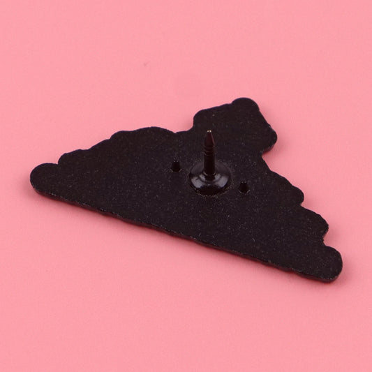 A black triangle pin-back badge with a central screw post, shown on a solid pink background.