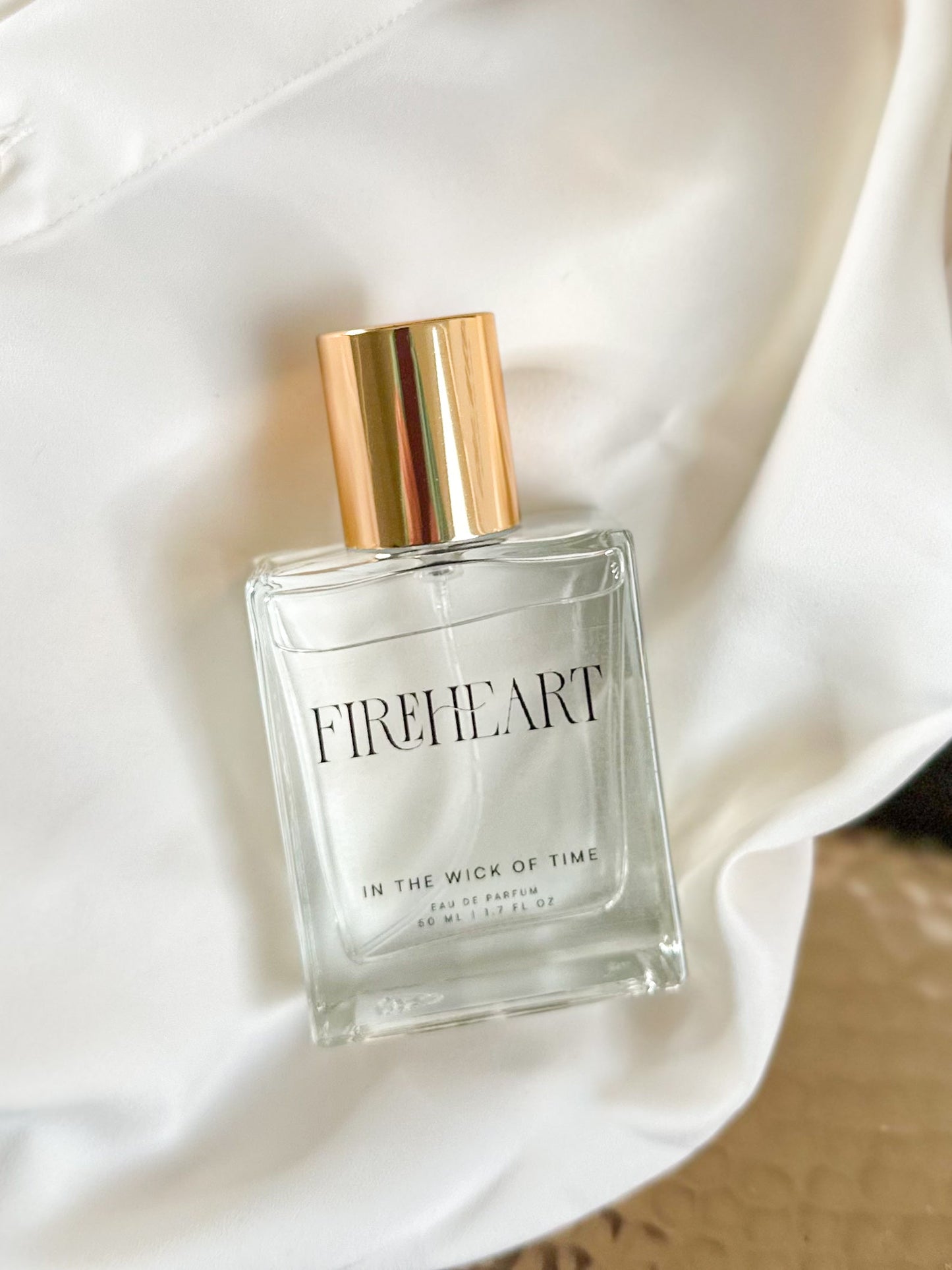 Perfume bottle labeled 'Fireheart' on a soft white fabric background