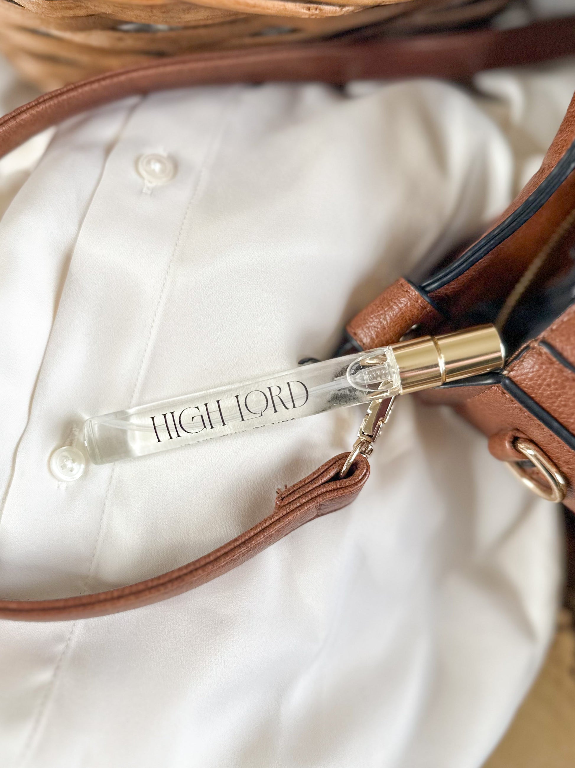 Small perfume bottle labeled 'High Lord' attached to a brown leather bag.