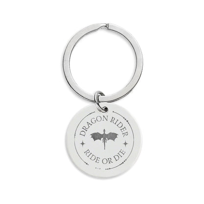 A silver metal keychain featuring a round disc charm engraved with the words 'DRAGON RIDER RIDE OR DIE' and a dragon silhouette, shown on a plain white background.