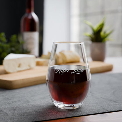 Stemless wine glass engraved with "High Lady" with red wine on a table with cheese and bread.