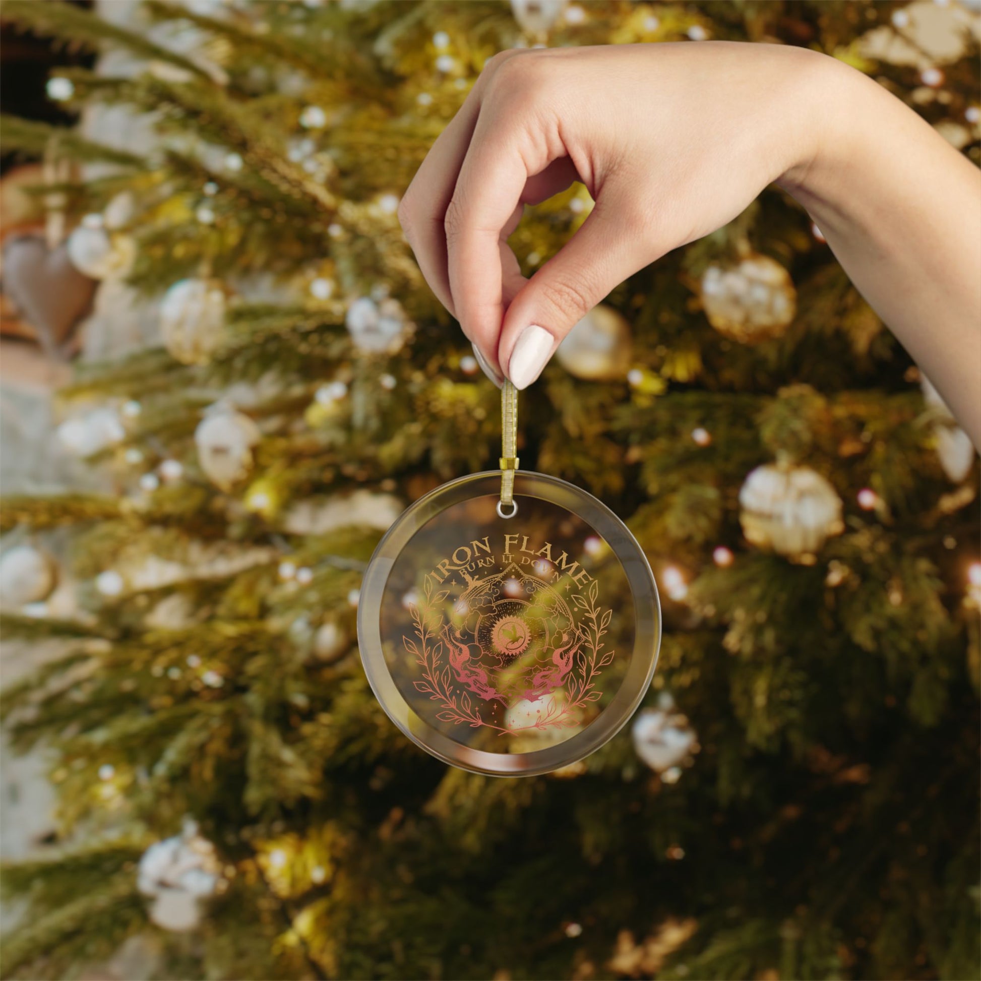 Hand holding a personalized Christmas ornament in front of a decorated tree