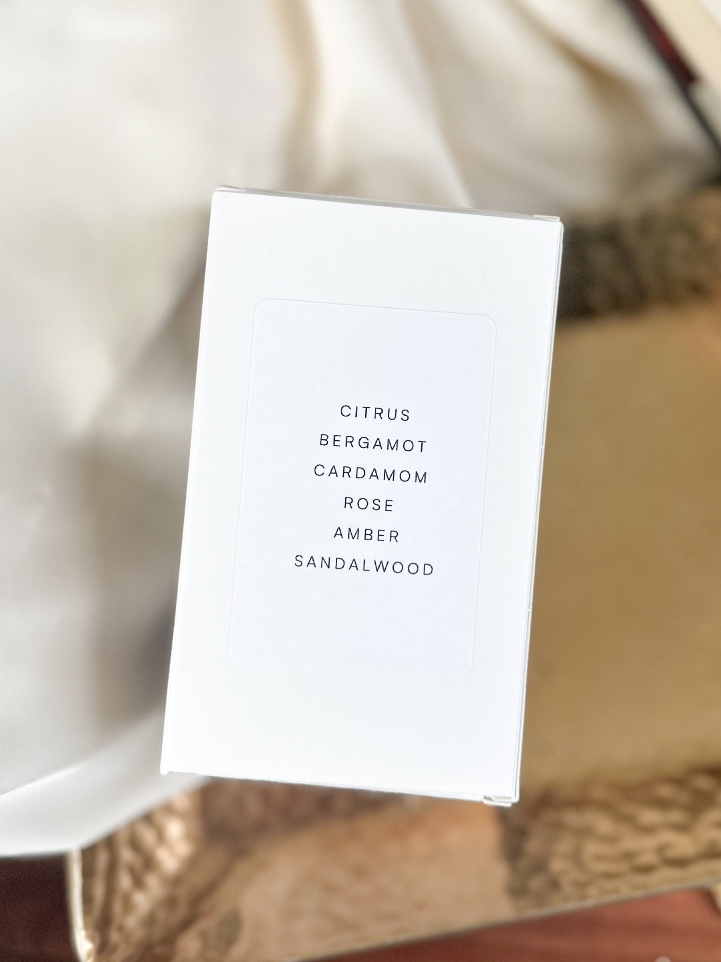 White perfume box, top view with fragrance notes on a textured surface 