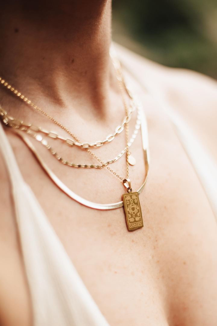 Close-up of a person wearing multiple gold necklaces with a focus on one pendant.