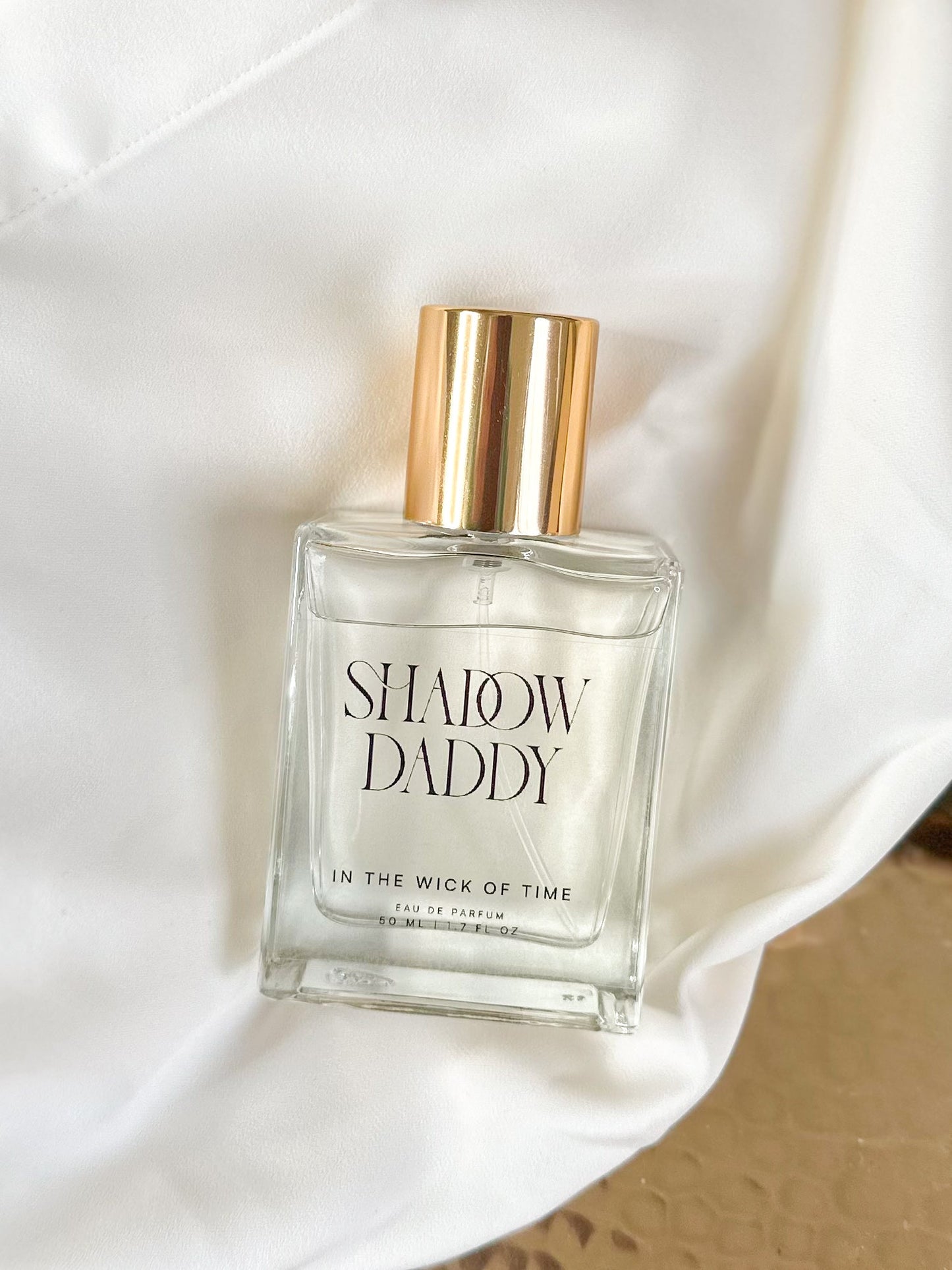 Perfume bottle labeled 'Shadow Daddy' on a white fabric background