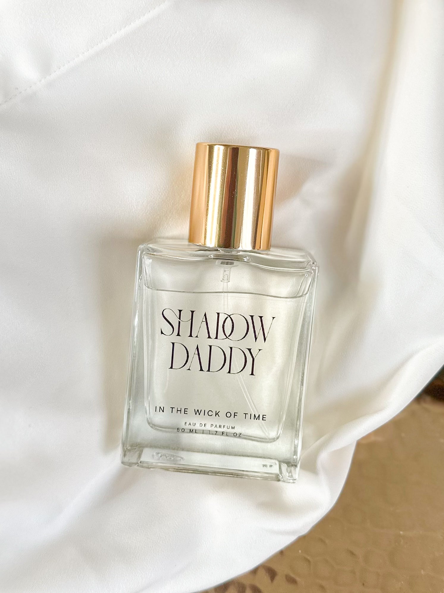 Perfume bottle labeled 'Shadow Daddy' on a white fabric background