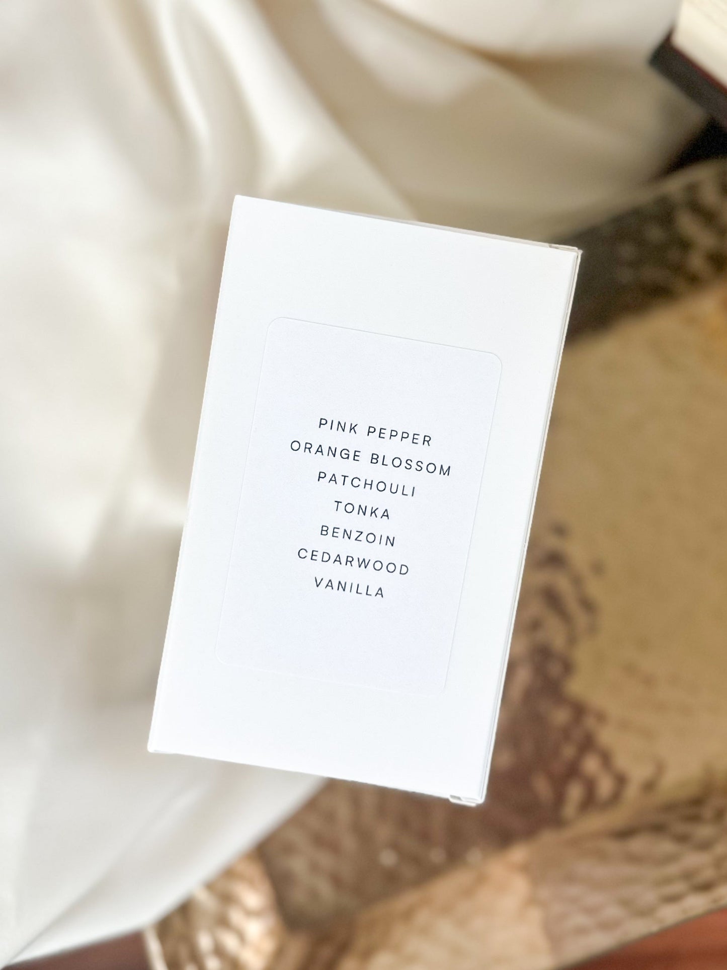 White card with fragrance notes on a textured surface