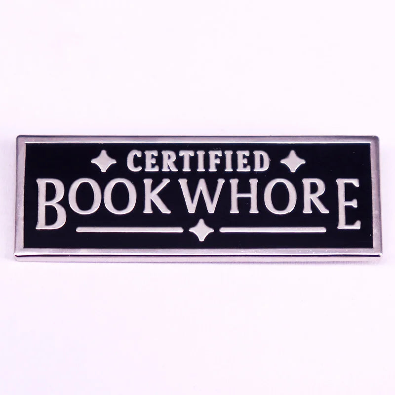 Enamel pin with 'Certified Bookwhore' text on a black background