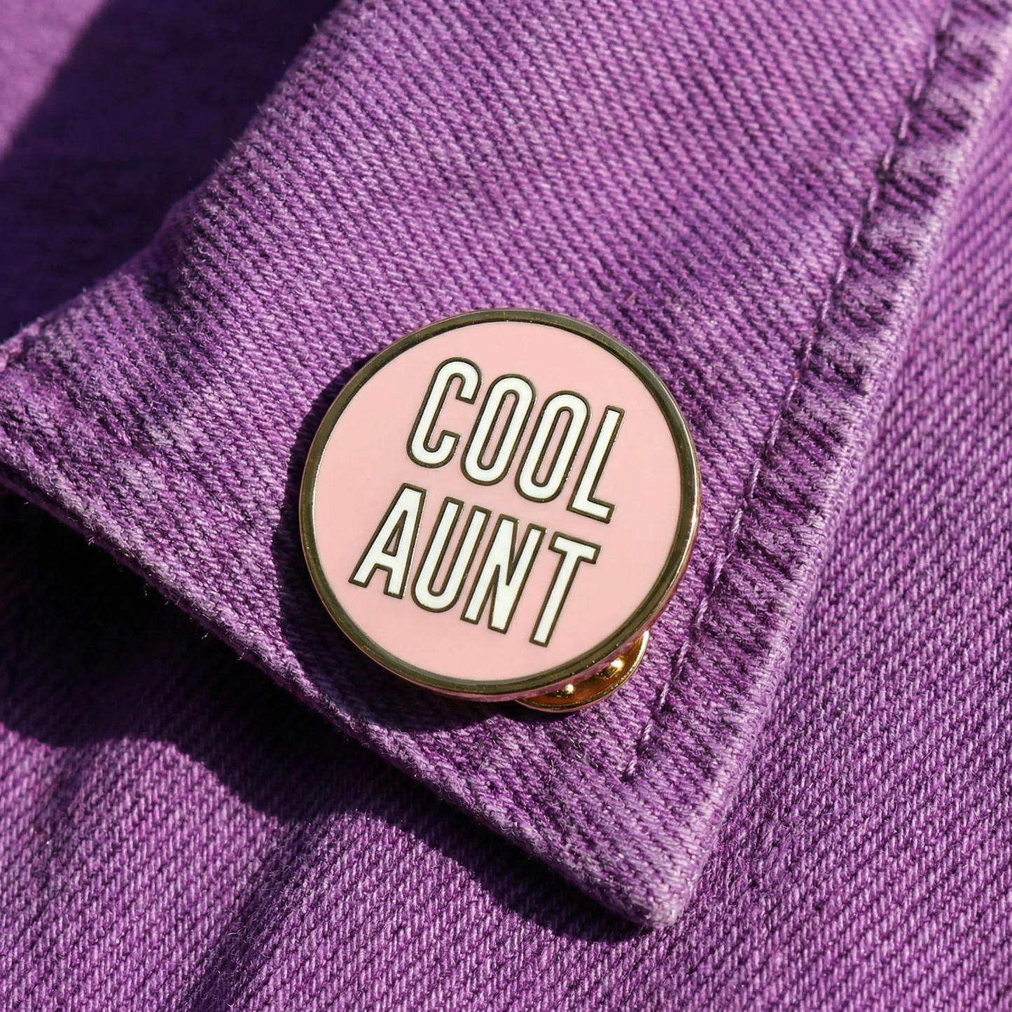 Pink 'Cool Aunt' pin on a purple denim jacket