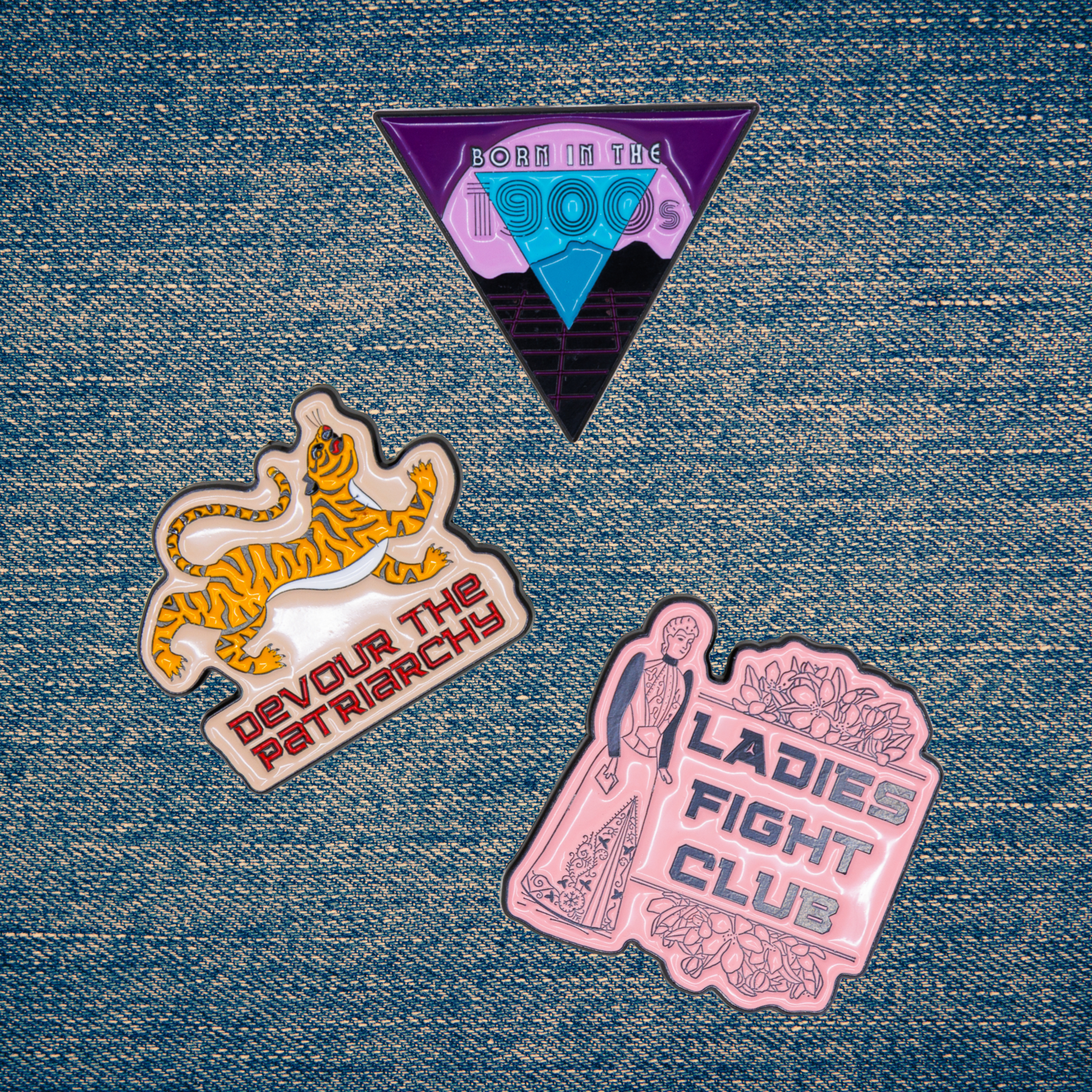Three protest-themed pins on a denim background