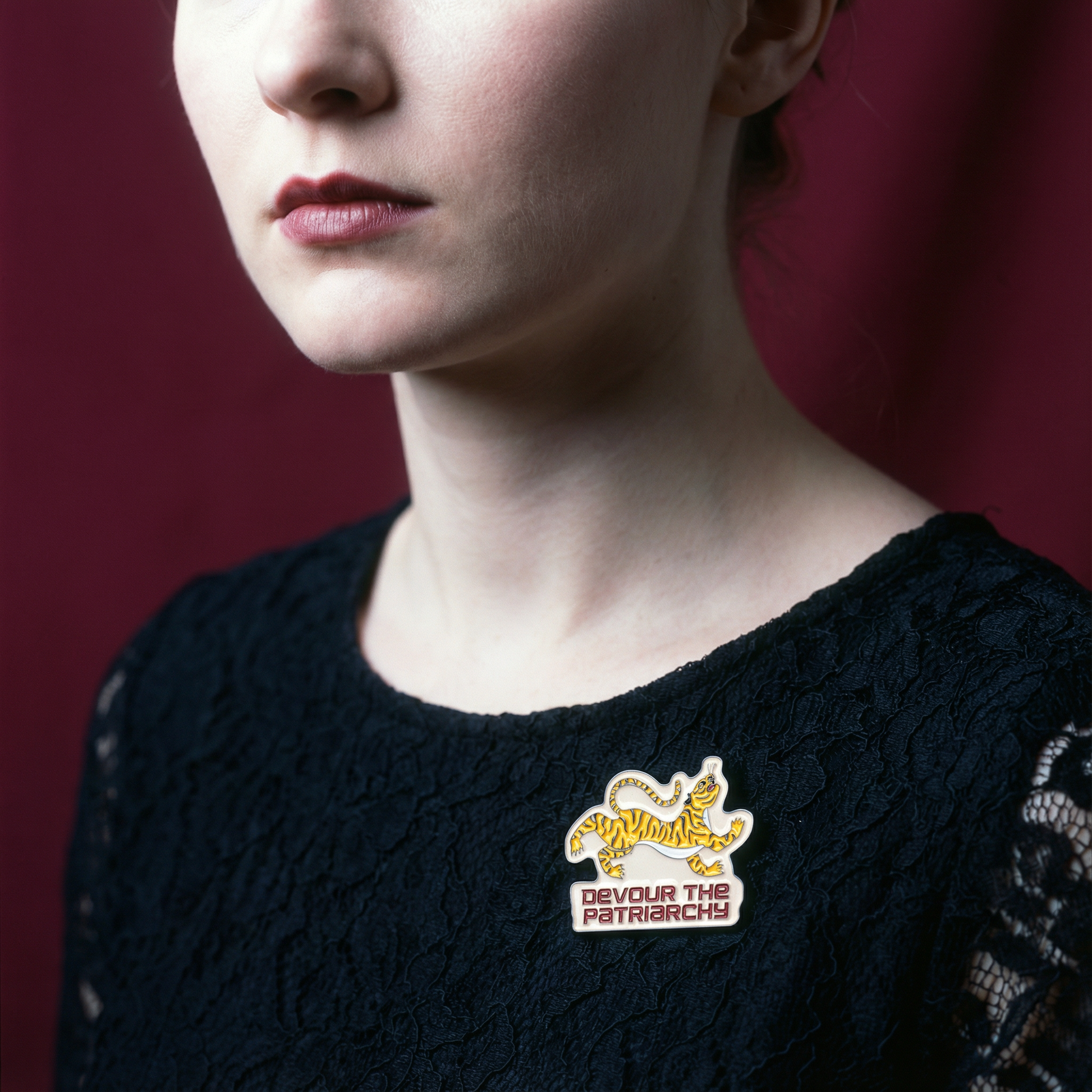 Person wearing a black sweater with a visible pin on a red background