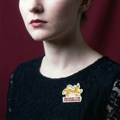 Person wearing a black sweater with a visible pin on a red background