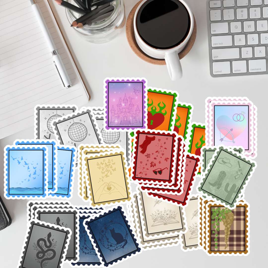 A flat-lay arrangement of colorful postage stamp designs on a white desk, surrounded by a keyboard, coffee cup, notebook, and pen.