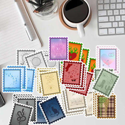 A flat-lay arrangement of colorful postage stamp designs on a white desk, surrounded by a keyboard, coffee cup, notebook, and pen.