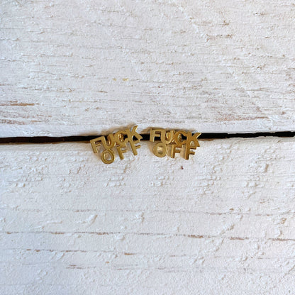 Gold necklace with 'F**K OFF' pendants on a textured white surface