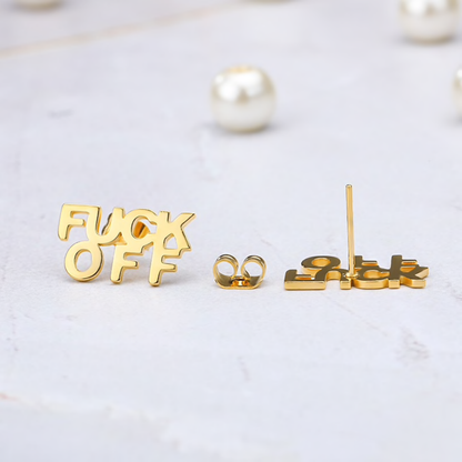 Gold earrings with censored text on a light background