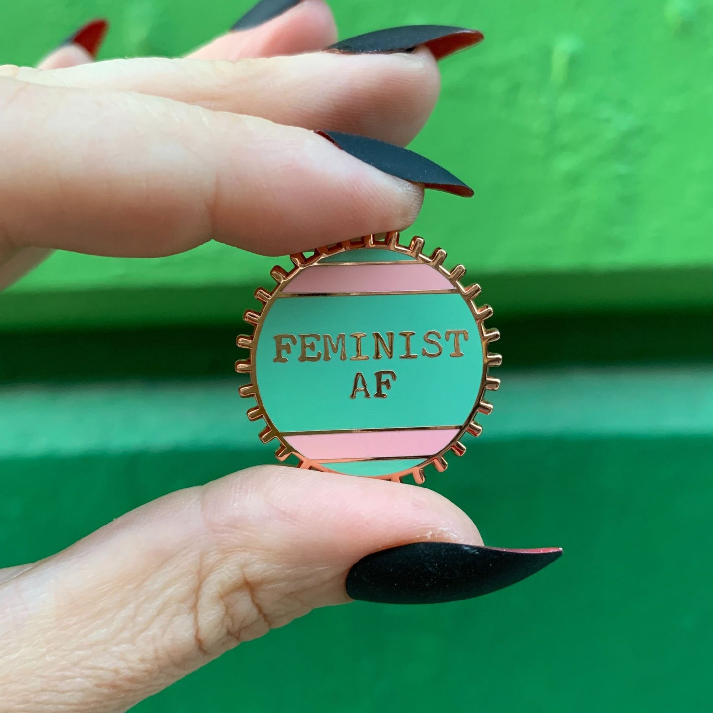 Feminist AF Enamel Pin by The Bullish Store in teal with gold metal and wheel design