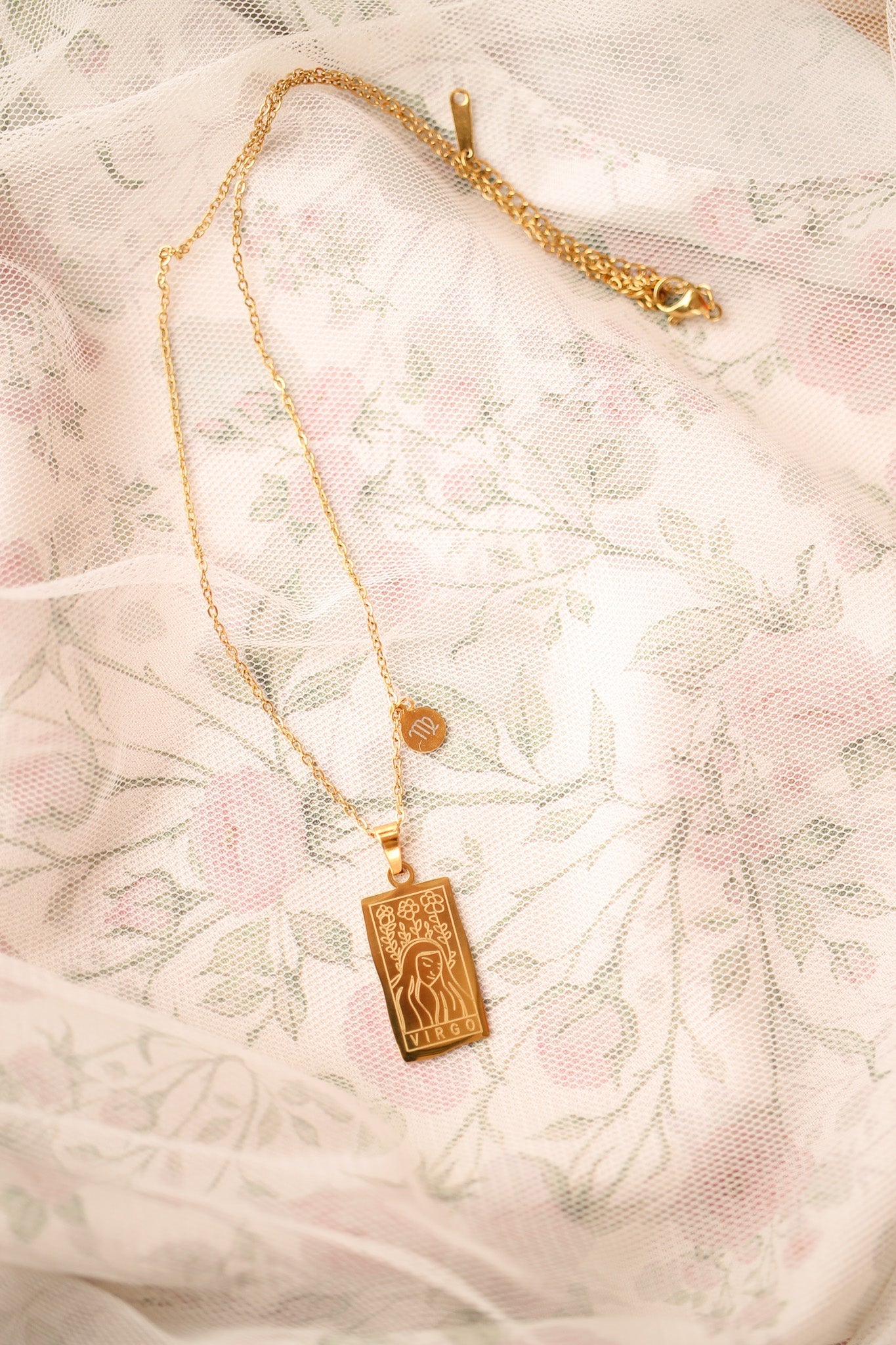 Gold necklace with a Zodiac pendant on a textured white background