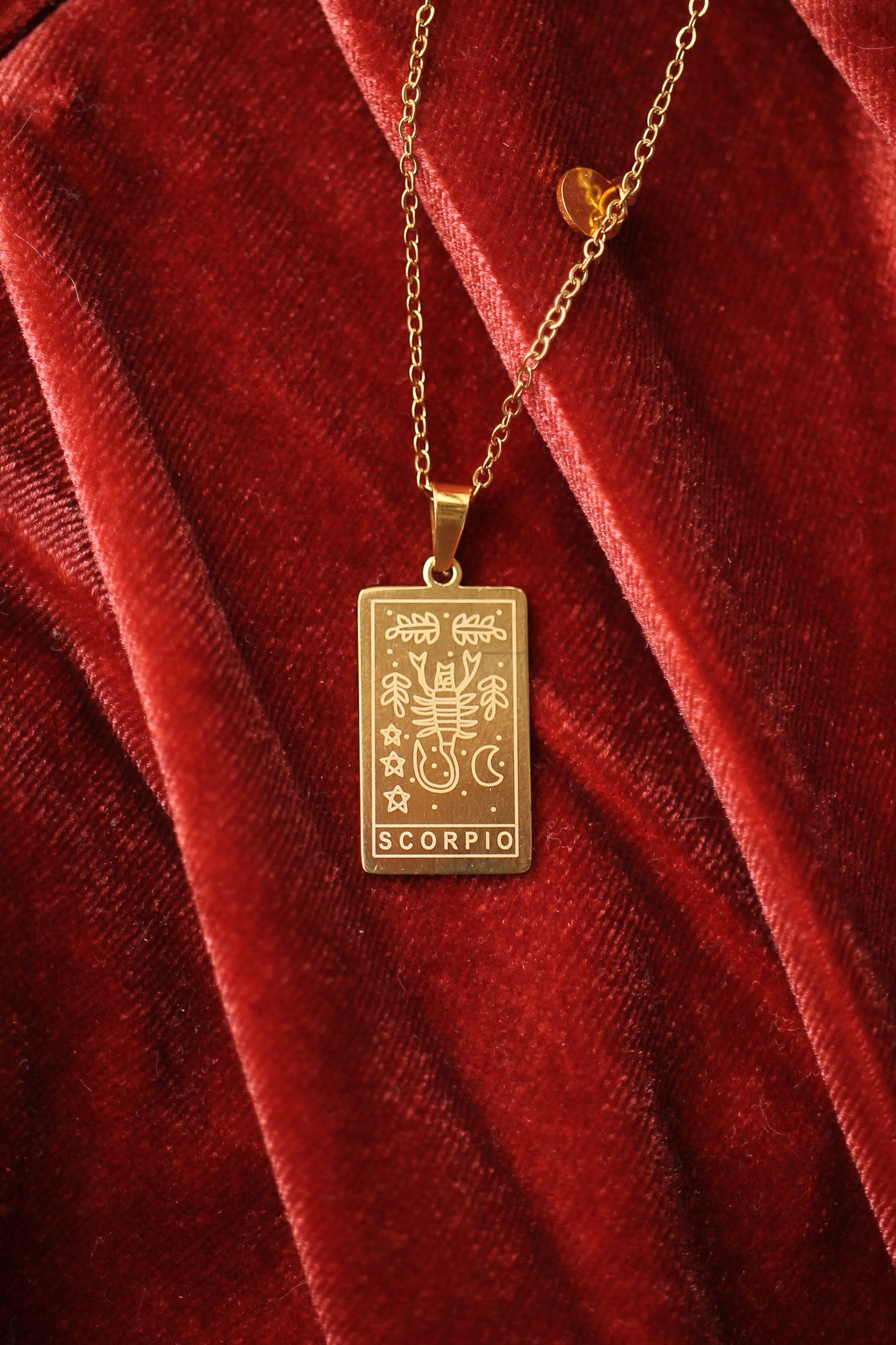 Gold Scorpio pendant necklace on a red velvet background