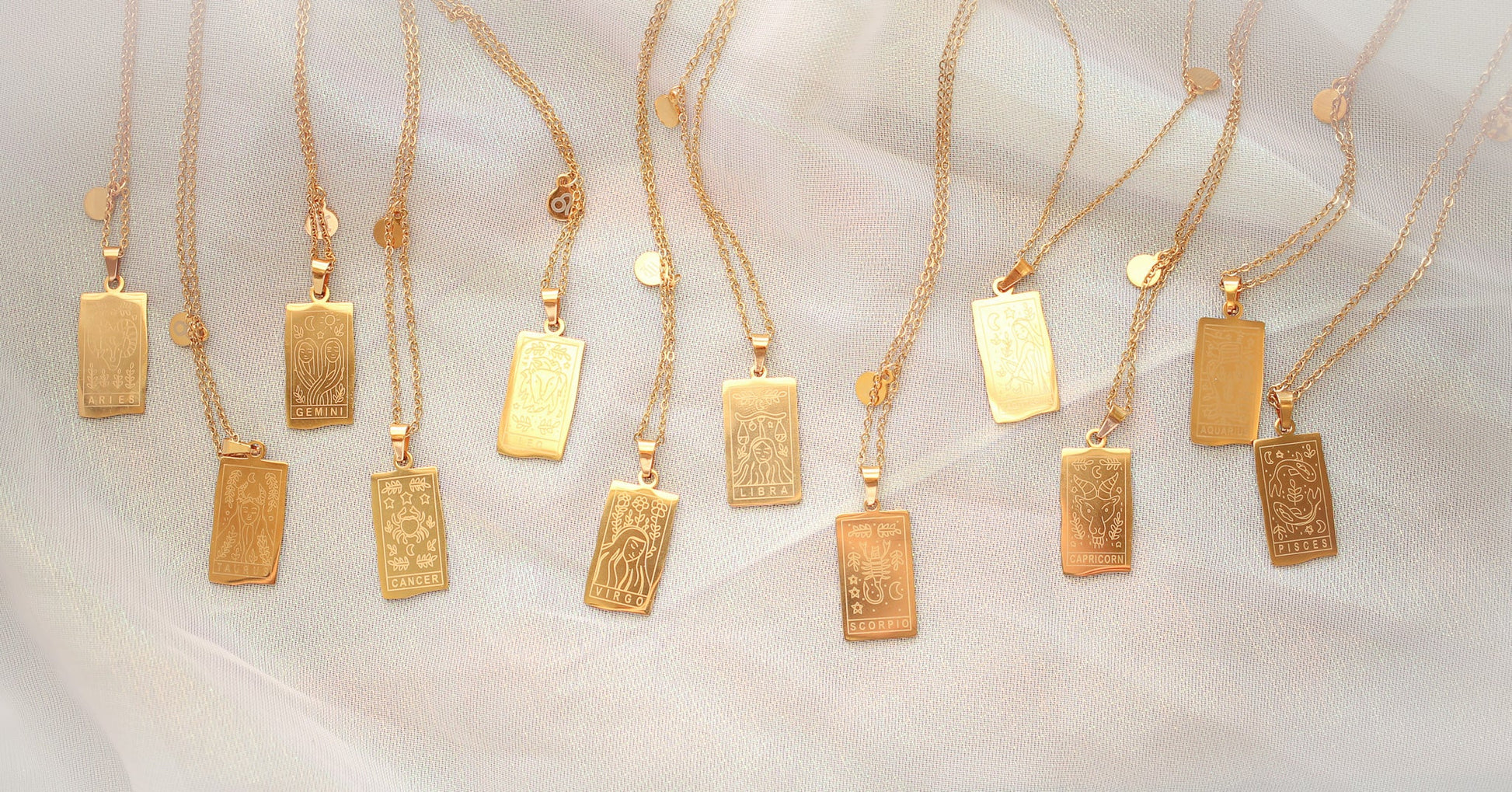 Gold necklaces with rectangular pendants, each featuring a 1 of 12 zodiac signs, on a white background.