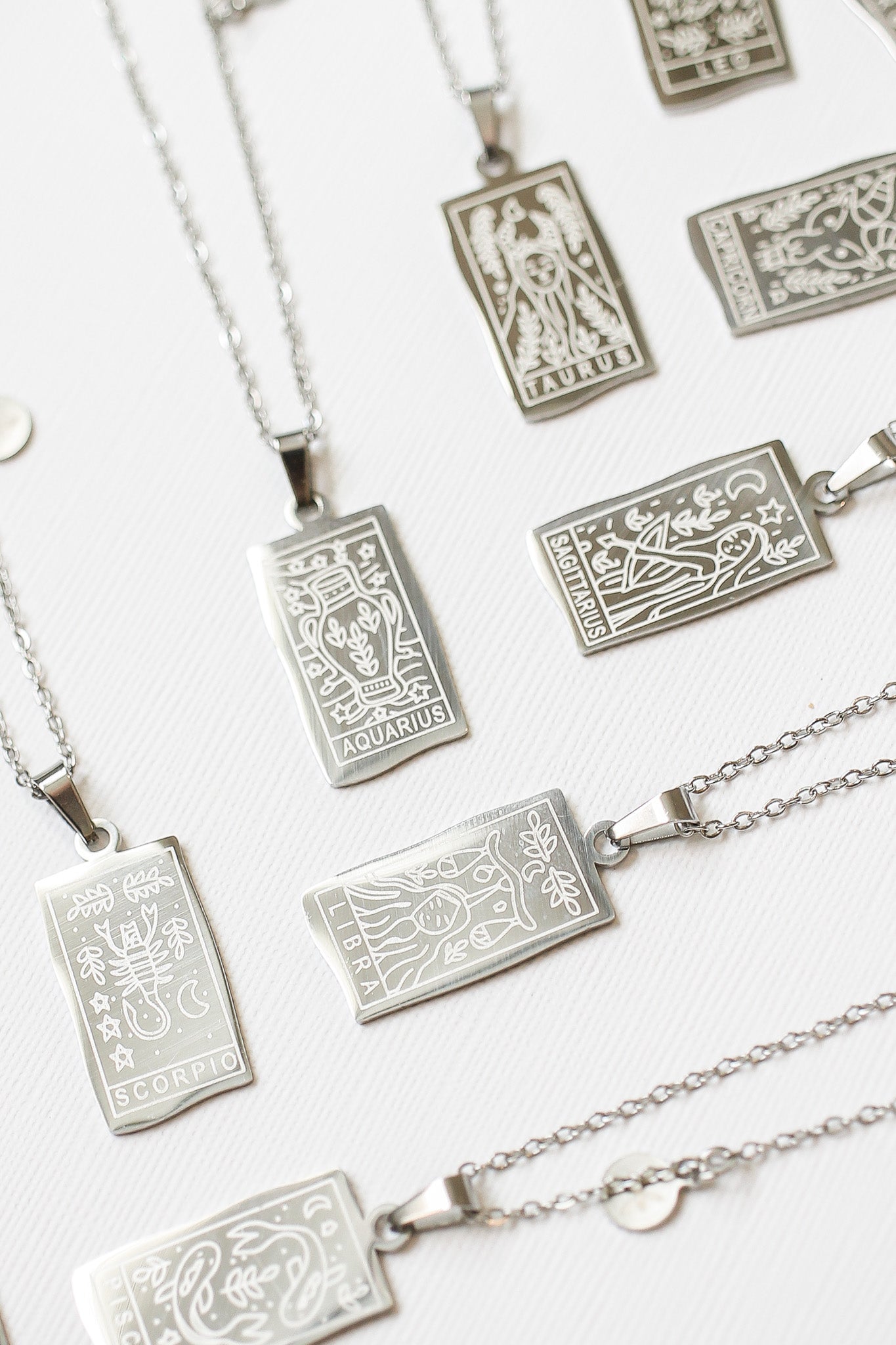 Silver zodiac pendant necklaces on a white background