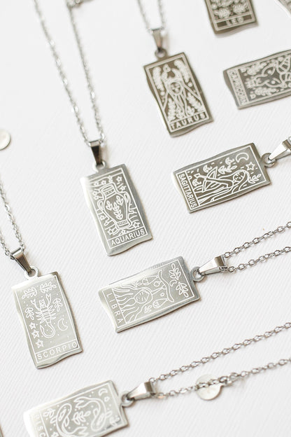 Silver zodiac pendant necklaces on a white background