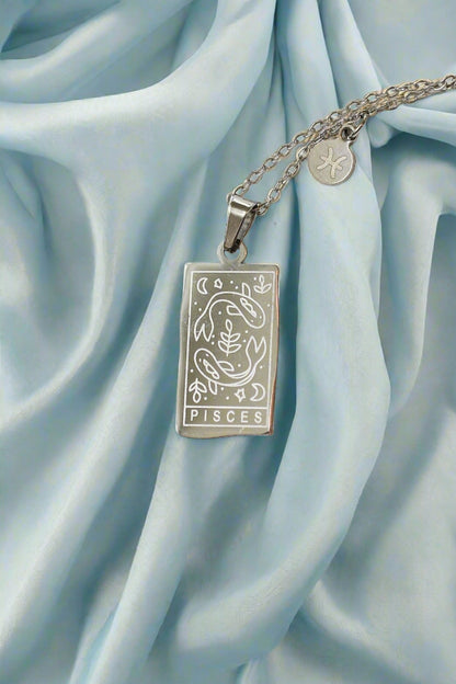 Silver Pisces zodiac pendant necklace on a light blue satin background