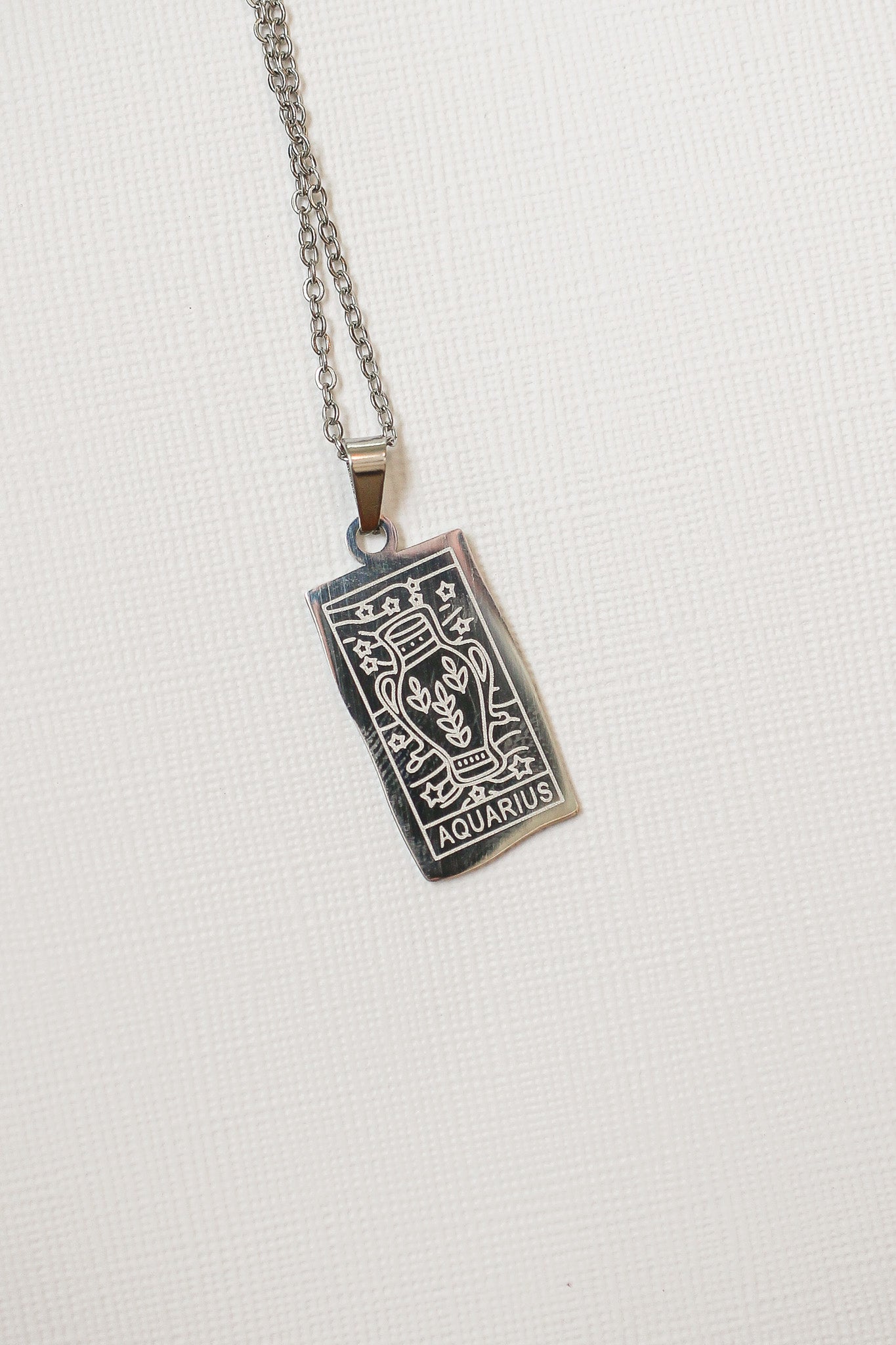 Aquarius zodiac sign pendant on a chain against a white background
