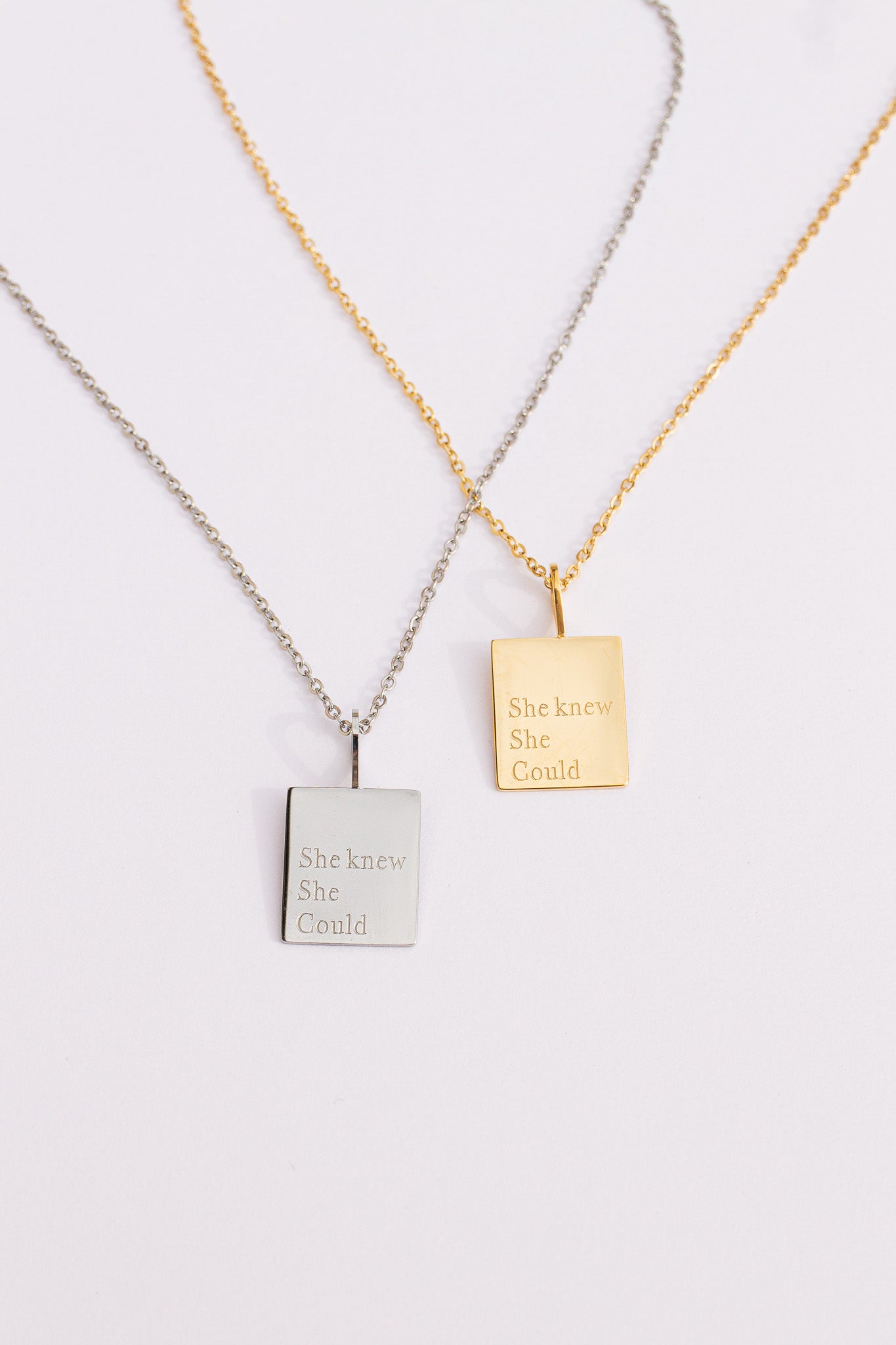 Two necklaces with square pendants on a light gray background