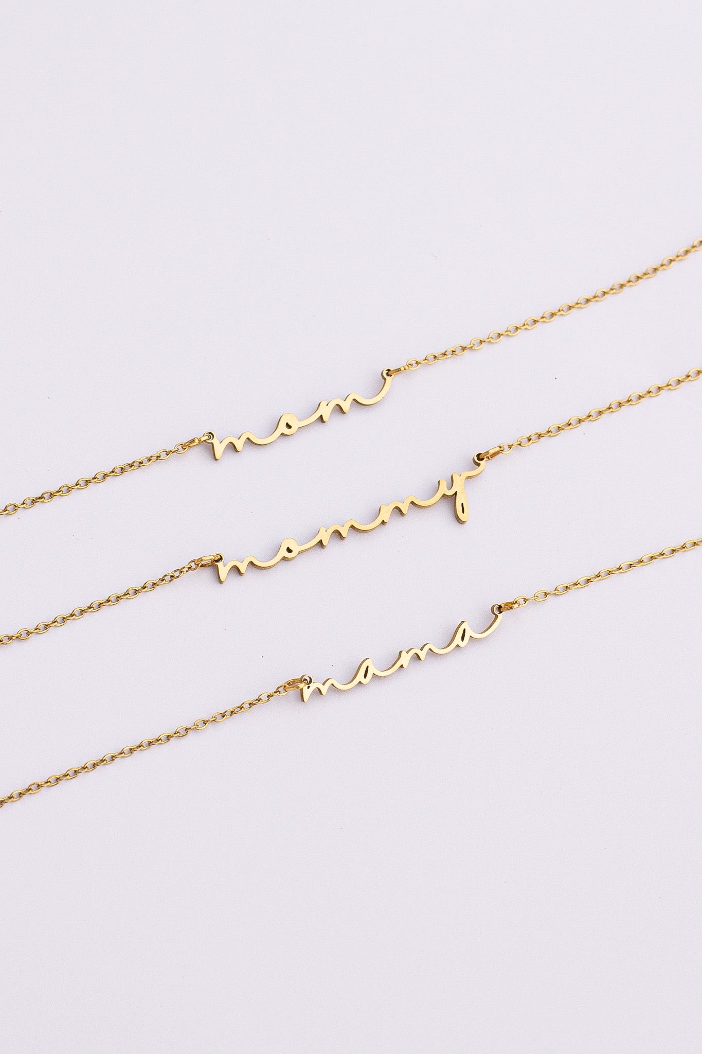 Three gold necklaces with heart designs on a light gray background