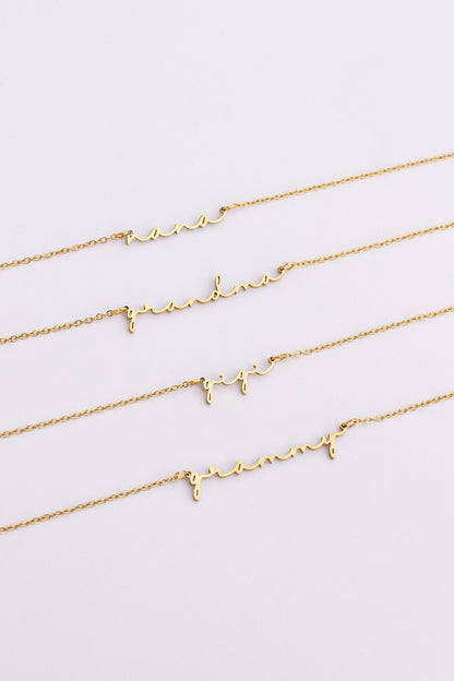 Three gold necklaces with letter pendants on a light gray background