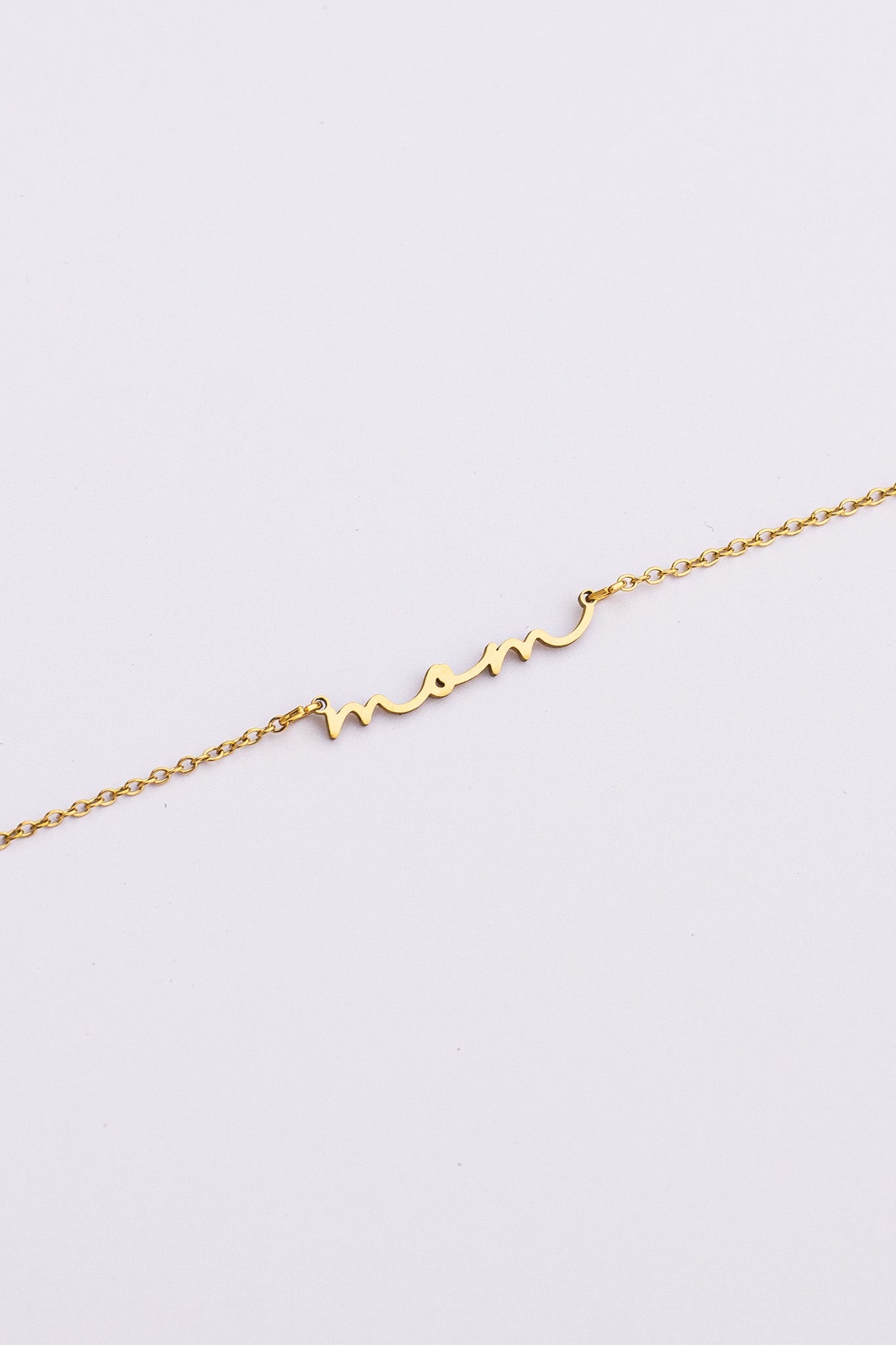 Gold bracelet with 'mom' inscription on a light gray background