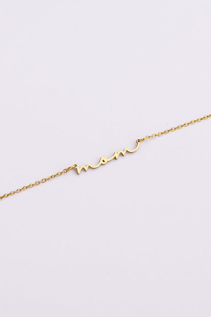 Gold bracelet with 'mom' inscription on a light gray background
