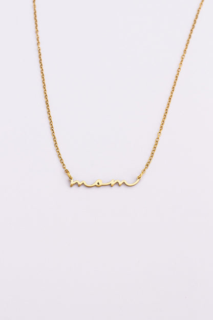 Gold necklace with 'mom' inscription on a light gray background