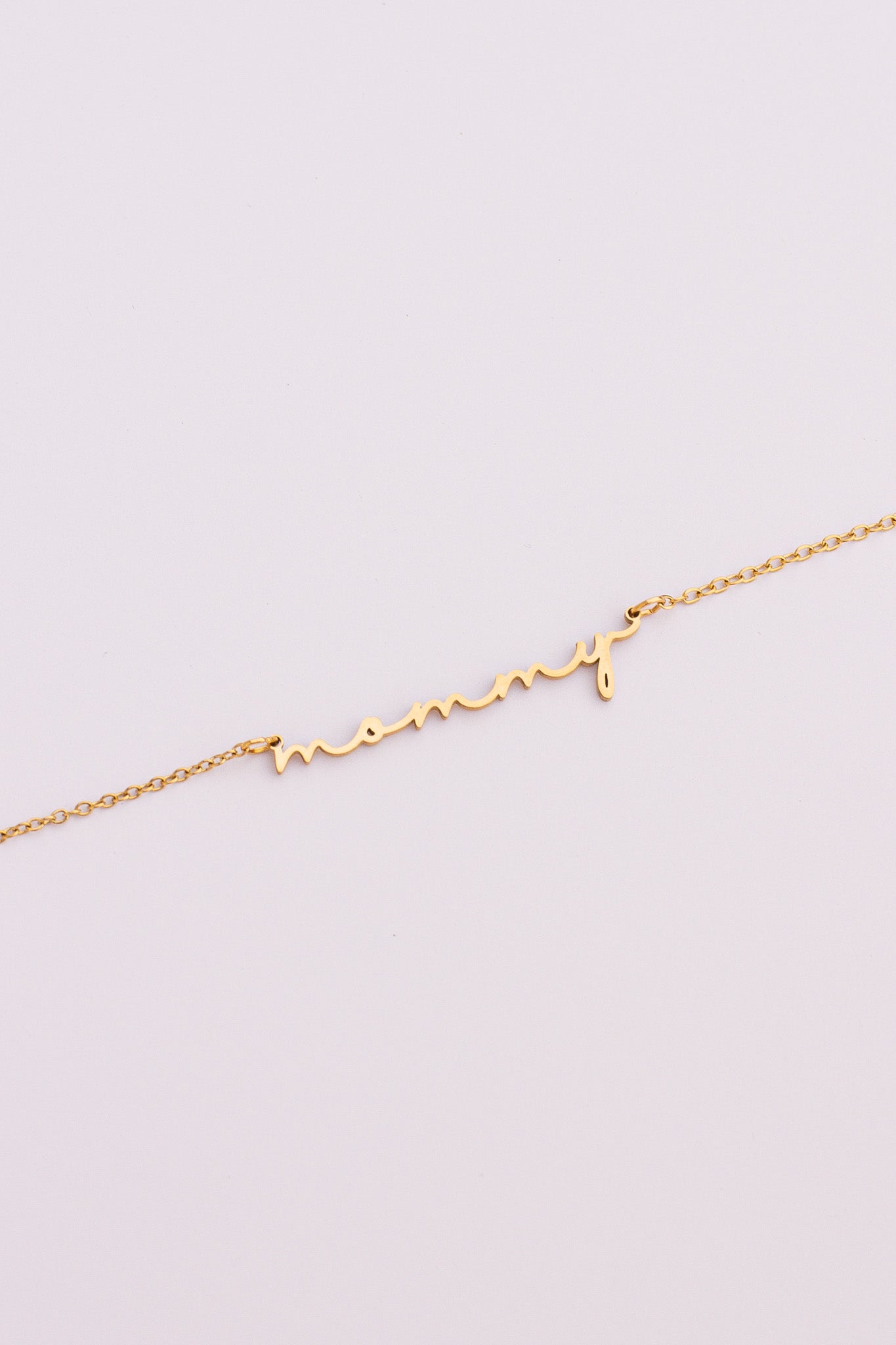 Gold "mommy" necklace on a light gray background