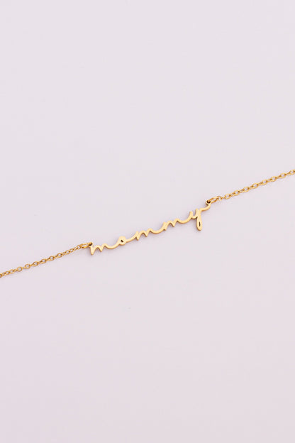 Gold "mommy" necklace on a light gray background