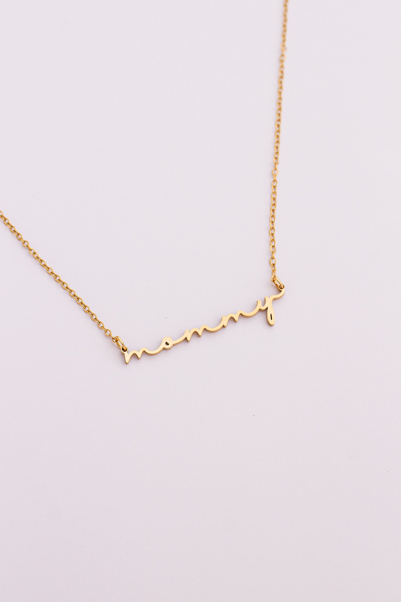Gold "mommy" necklace on a light pink background