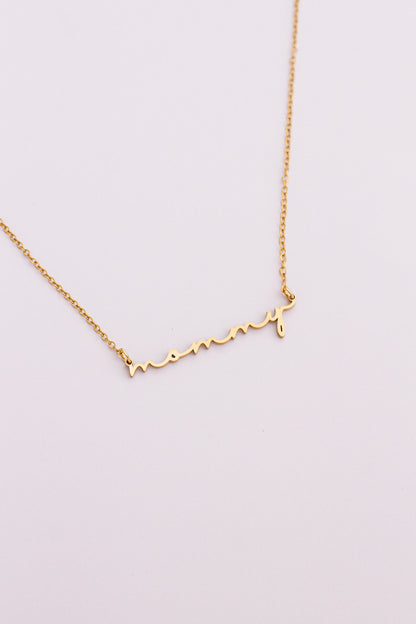 Gold "mommy" necklace on a light pink background