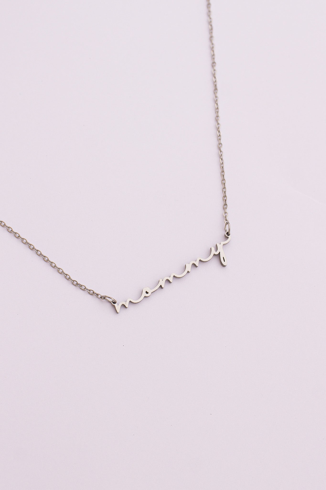 Silver necklace with heart-shaped charms on a light pink background
