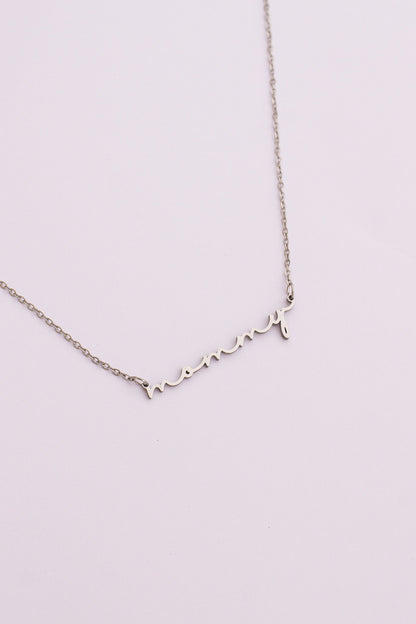 Silver necklace with heart-shaped charms on a light pink background