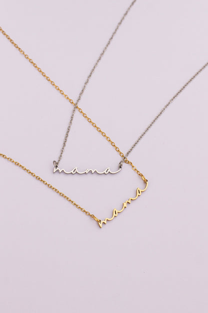 Two gold necklaces with 'mama' and heart designs on a light purple background