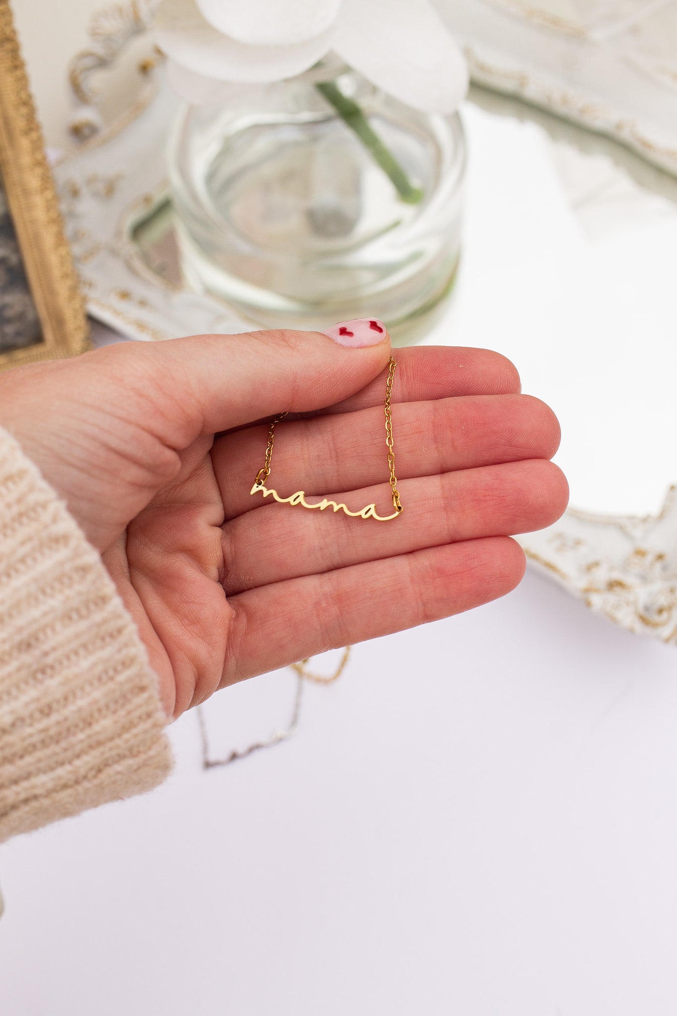 Gold necklace being held in a hand with a blurred background