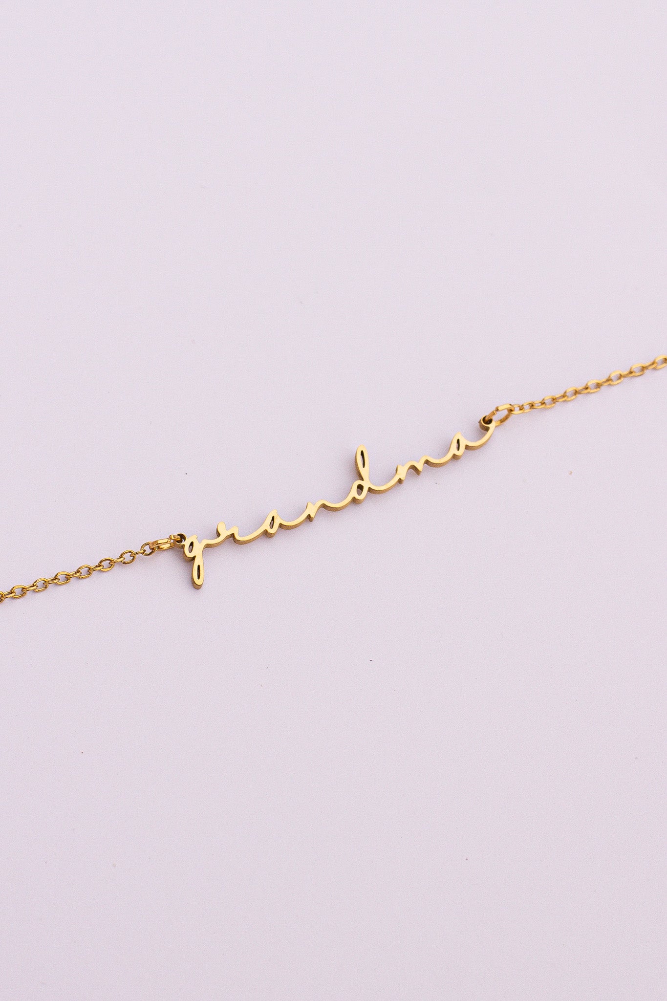 Gold bracelet with heart and letter 'L' on a light purple background