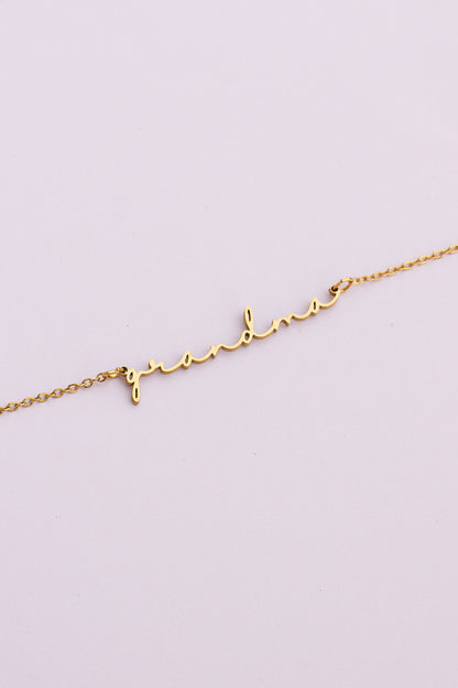 Gold bracelet with heart and letter 'L' on a light purple background