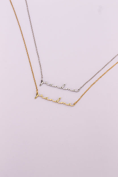 Two gold necklaces with 'grandma' engraved on a light pink background