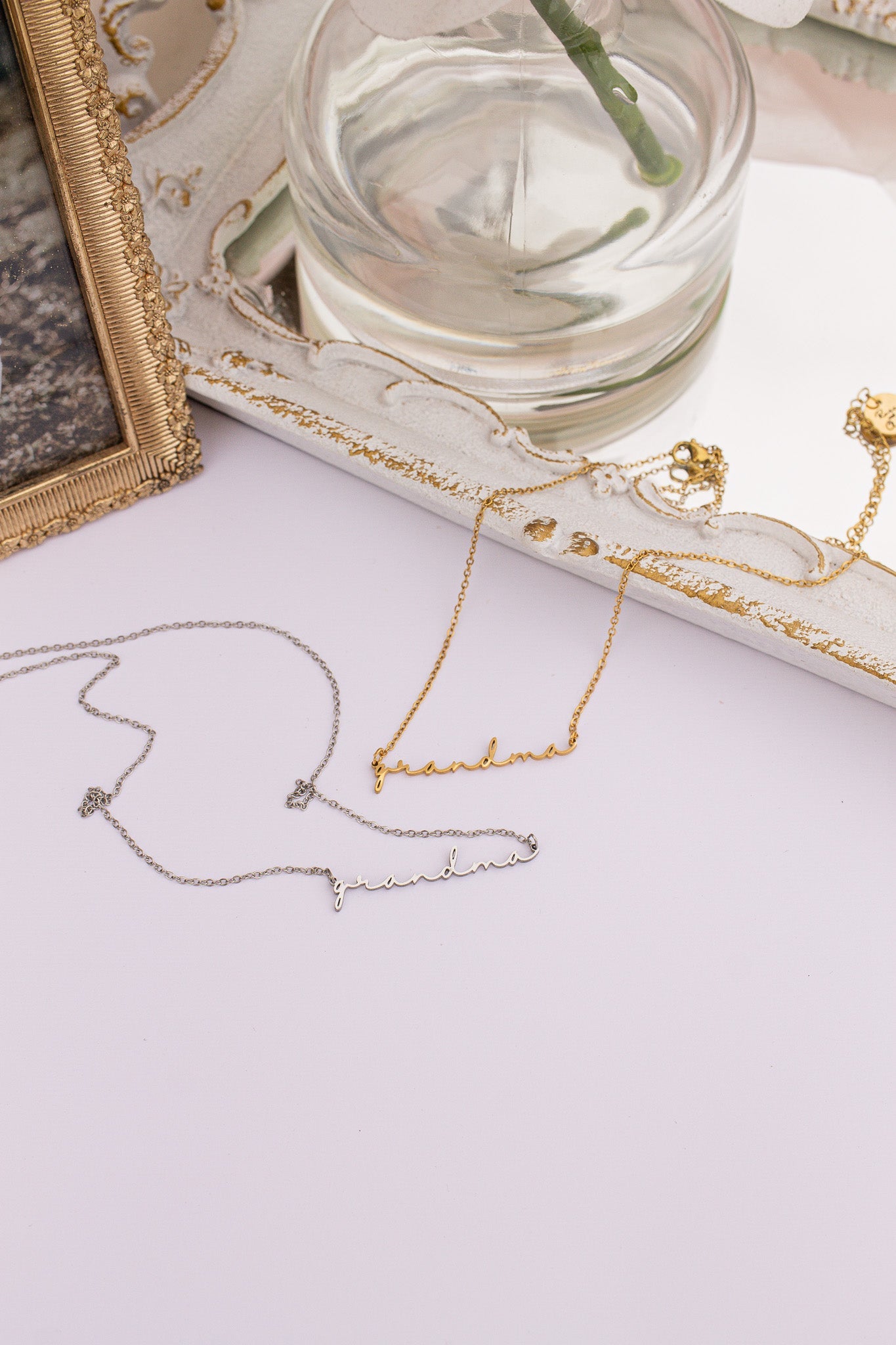 Jewelry including necklaces and a small framed picture on a light surface.